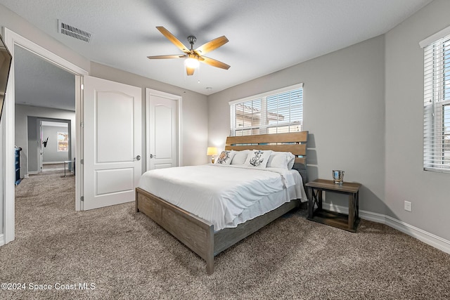 bedroom featuring carpet flooring, a textured ceiling, multiple windows, and ceiling fan