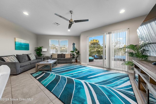 living room with tile patterned floors, ceiling fan, and a textured ceiling