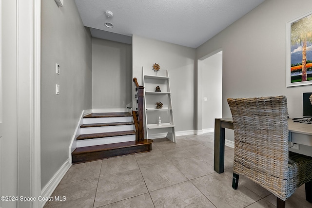 stairway with tile patterned flooring and a textured ceiling