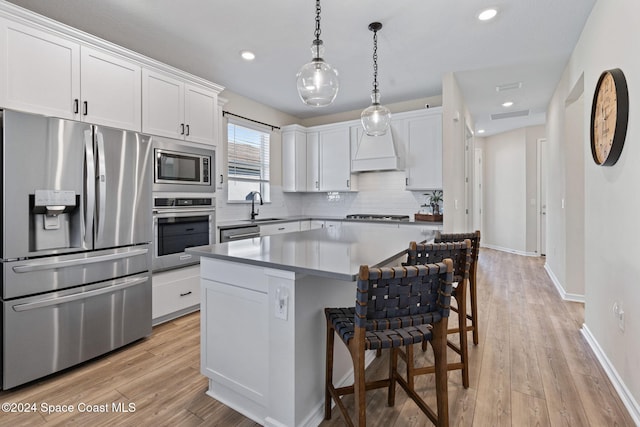 kitchen with sink, hanging light fixtures, appliances with stainless steel finishes, light hardwood / wood-style floors, and white cabinetry