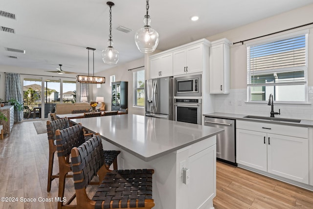 kitchen with appliances with stainless steel finishes, light hardwood / wood-style floors, white cabinetry, and sink