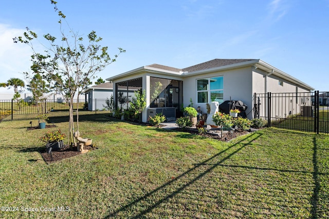 rear view of property featuring a sunroom and a yard