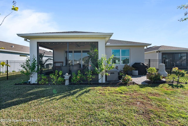 back of property with a sunroom, ceiling fan, and a yard