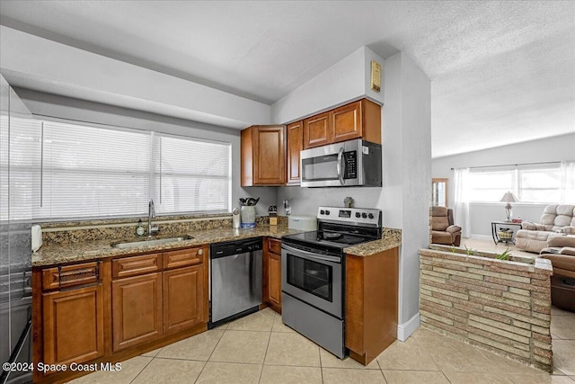 kitchen featuring stainless steel appliances, vaulted ceiling, dark stone counters, and sink