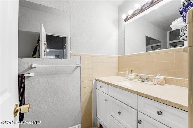 bathroom featuring vanity and tile walls