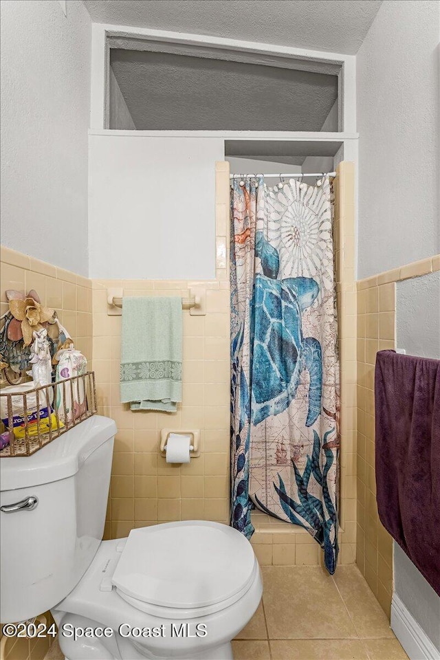 bathroom featuring tile patterned flooring, a textured ceiling, toilet, tile walls, and a shower with shower curtain