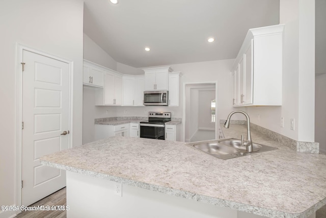 kitchen with kitchen peninsula, sink, white cabinets, and stainless steel appliances