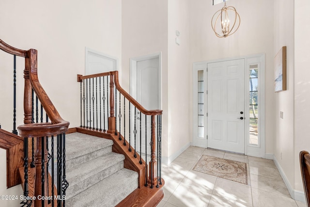 foyer with a towering ceiling, light tile patterned floors, and an inviting chandelier