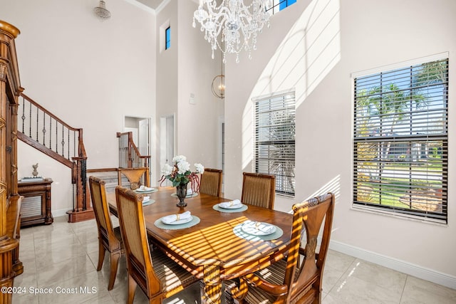 dining area featuring light tile patterned floors, a towering ceiling, an inviting chandelier, and ornamental molding