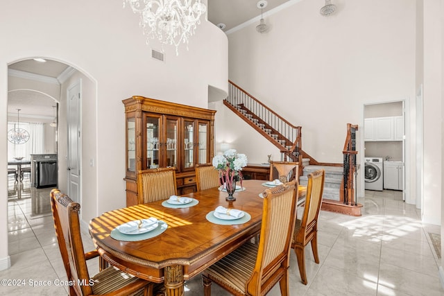 dining area with a chandelier, a towering ceiling, washer and dryer, and ornamental molding