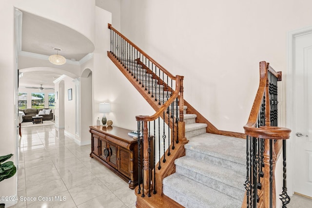 stairway with ceiling fan and ornamental molding