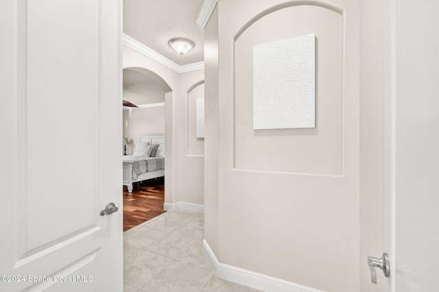 corridor featuring light tile patterned flooring, ornamental molding, and a textured ceiling