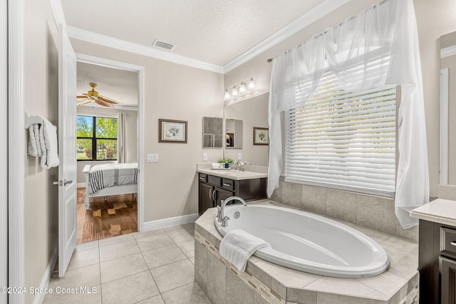 bathroom with vanity, tile patterned flooring, ornamental molding, a textured ceiling, and tiled tub