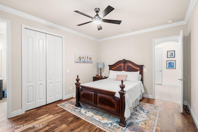 bedroom with a closet, ceiling fan, hardwood / wood-style floors, and ornamental molding