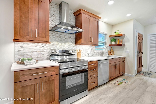 kitchen with sink, light hardwood / wood-style flooring, wall chimney exhaust hood, tasteful backsplash, and stainless steel appliances