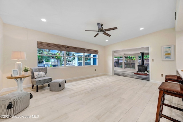 living area with ceiling fan, light wood-type flooring, and a wood stove