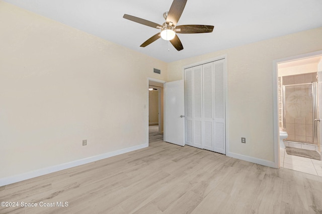 unfurnished bedroom featuring ensuite bathroom, ceiling fan, light wood-type flooring, and a closet