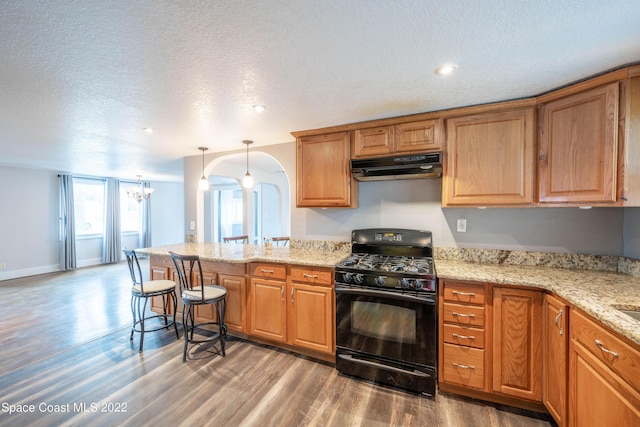 kitchen with hanging light fixtures, an inviting chandelier, black gas stove, a textured ceiling, and hardwood / wood-style flooring