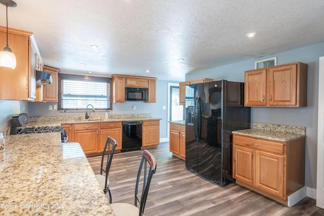 kitchen featuring sink, dark wood-type flooring, pendant lighting, a textured ceiling, and black appliances