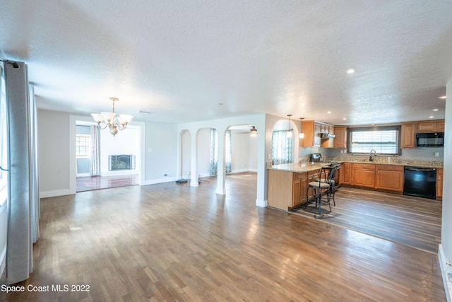 kitchen with black appliances, pendant lighting, dark hardwood / wood-style flooring, and kitchen peninsula