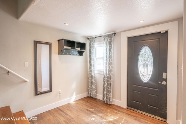 entrance foyer with a textured ceiling and light hardwood / wood-style flooring