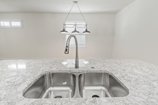 interior details featuring light stone counters, sink, and hanging light fixtures