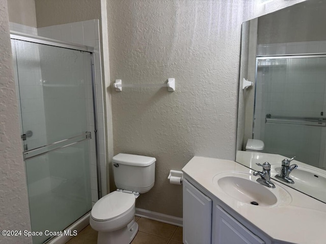 bathroom featuring tile patterned floors, vanity, toilet, and walk in shower