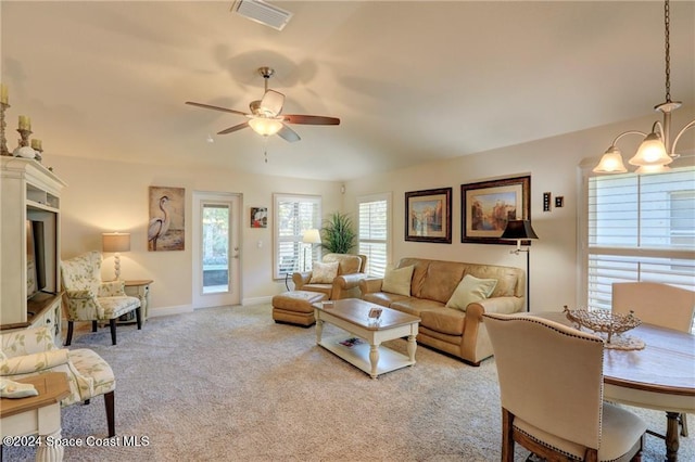 living room featuring light carpet and ceiling fan with notable chandelier