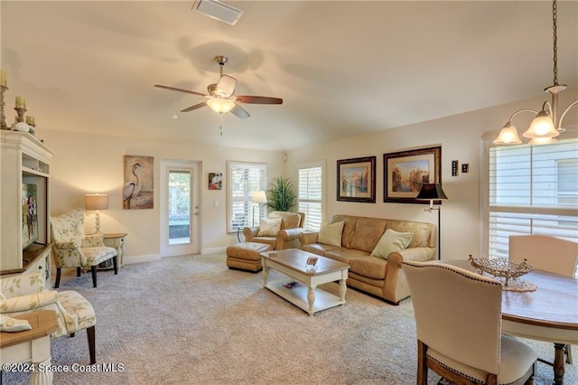 carpeted living room featuring ceiling fan with notable chandelier