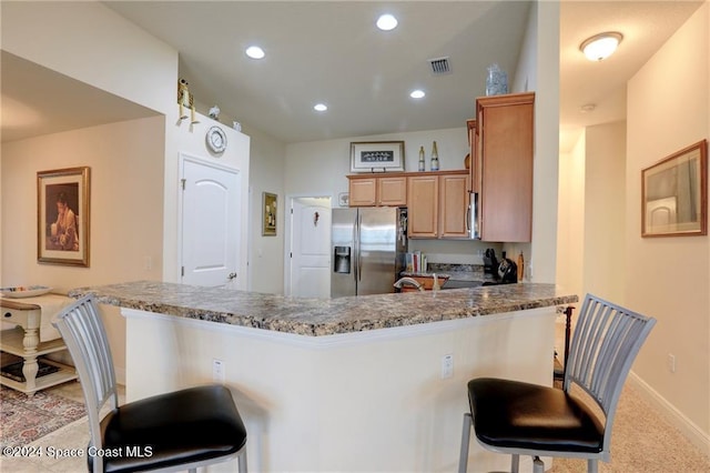 kitchen with a kitchen bar, kitchen peninsula, light colored carpet, and appliances with stainless steel finishes