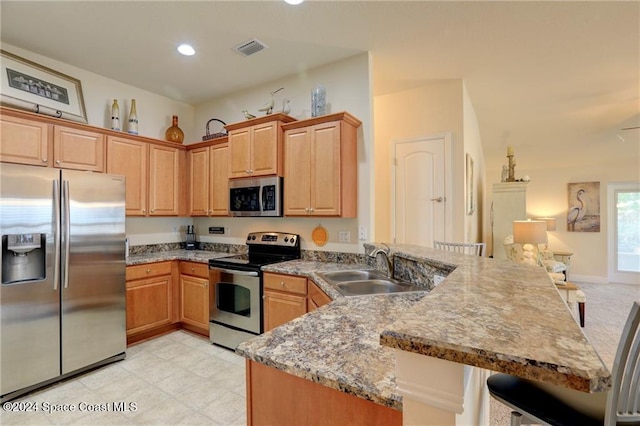 kitchen featuring sink, light stone countertops, appliances with stainless steel finishes, kitchen peninsula, and a breakfast bar area