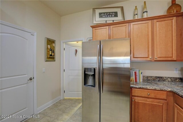 kitchen featuring stainless steel fridge with ice dispenser and dark stone countertops