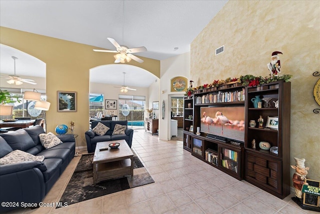 tiled living room with ceiling fan and high vaulted ceiling