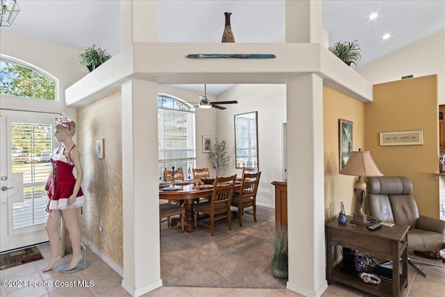 tiled dining space featuring ceiling fan and high vaulted ceiling