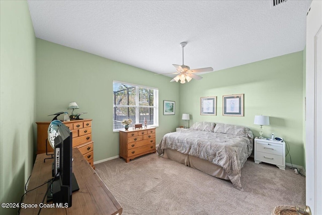 carpeted bedroom with ceiling fan and a textured ceiling