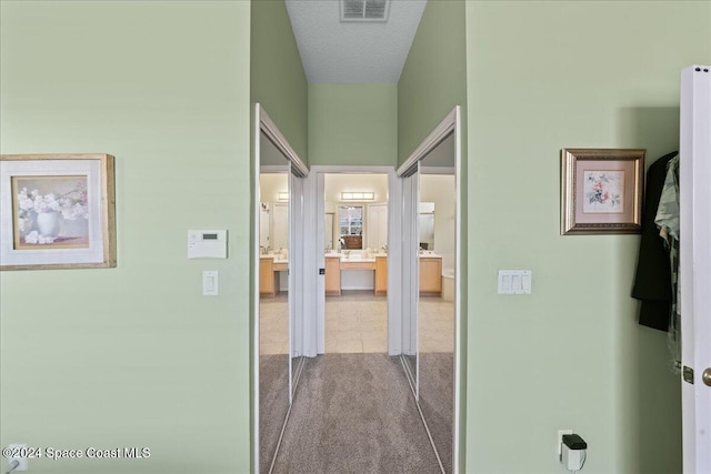 hallway with light carpet and a textured ceiling