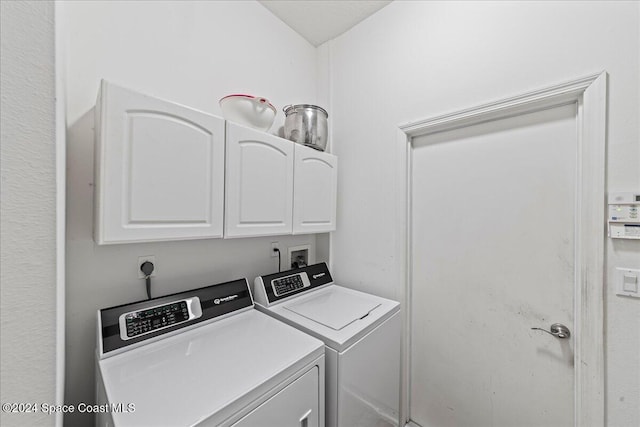 clothes washing area featuring cabinets and washer and dryer