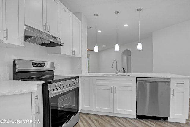 kitchen with appliances with stainless steel finishes, sink, decorative light fixtures, white cabinets, and light hardwood / wood-style floors