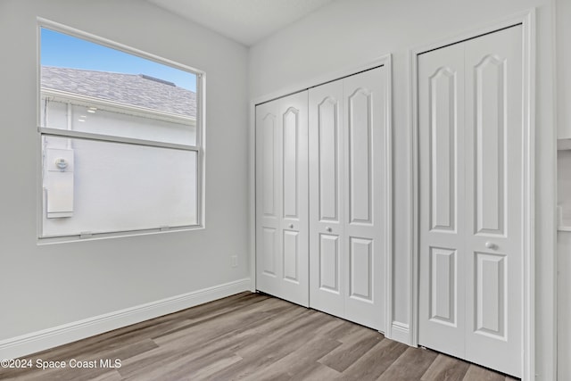 unfurnished bedroom featuring light hardwood / wood-style floors and multiple closets