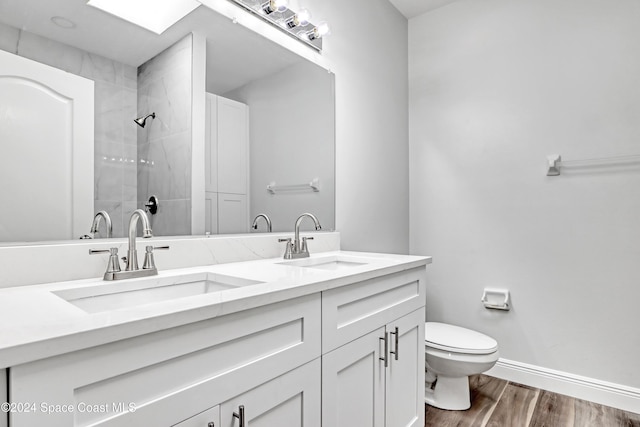 bathroom featuring tiled shower, wood-type flooring, vanity, and toilet