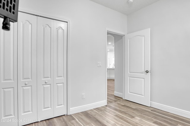 unfurnished bedroom featuring light hardwood / wood-style floors, a textured ceiling, and a closet