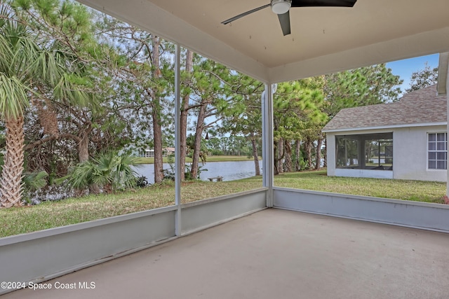 unfurnished sunroom featuring ceiling fan and a water view