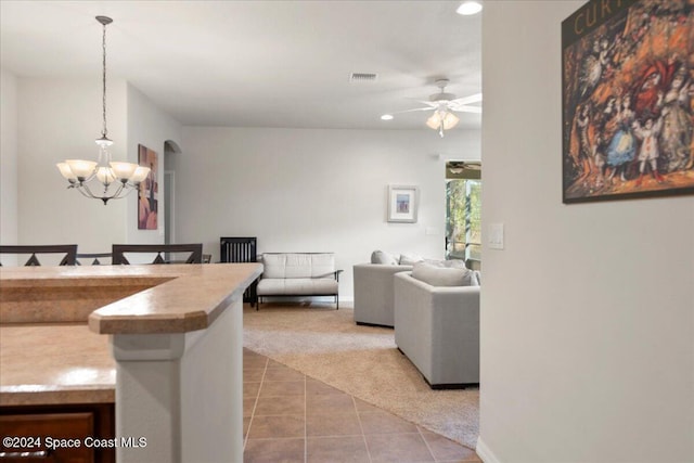 carpeted living room featuring ceiling fan with notable chandelier