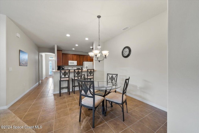 tiled dining area featuring a chandelier