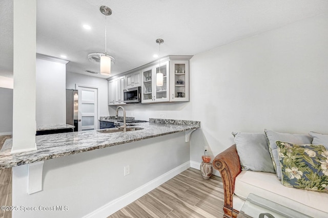 kitchen with kitchen peninsula, stainless steel appliances, sink, decorative light fixtures, and white cabinetry