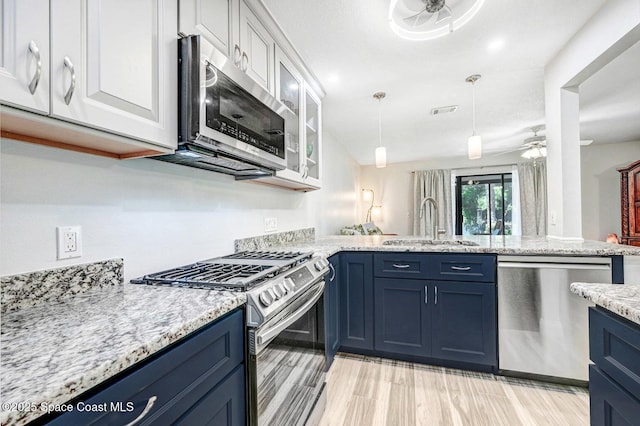 kitchen with appliances with stainless steel finishes, blue cabinets, ceiling fan, sink, and white cabinets