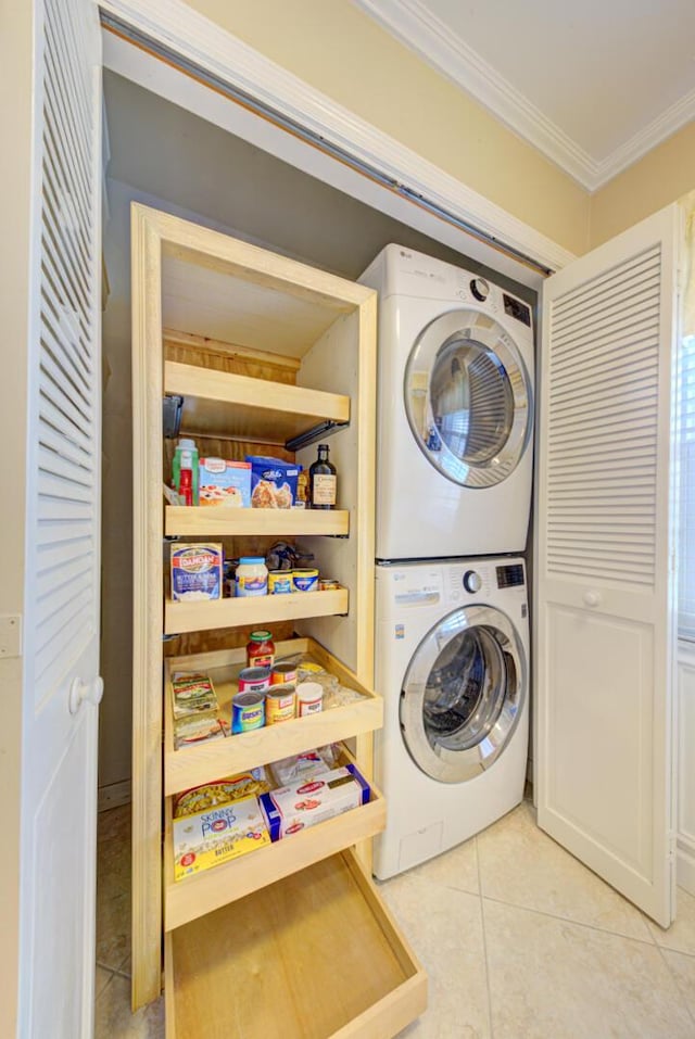 laundry area featuring crown molding, stacked washer / drying machine, and light tile patterned flooring