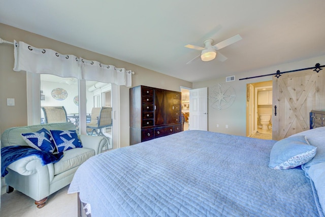 bedroom with ceiling fan, a barn door, and ensuite bath