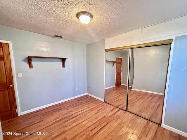 unfurnished bedroom with a closet, hardwood / wood-style floors, and a textured ceiling