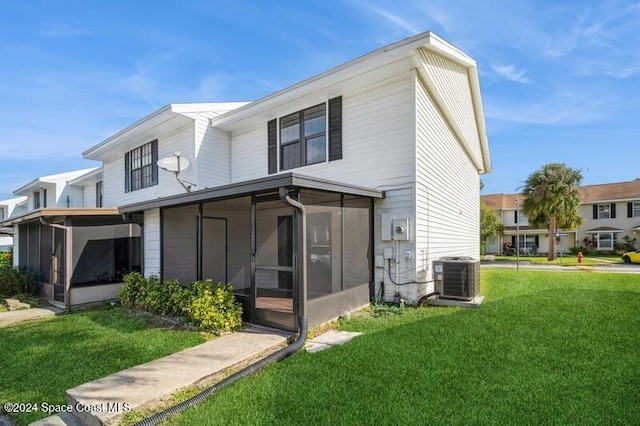 view of front of house with a sunroom, a front lawn, and central AC unit